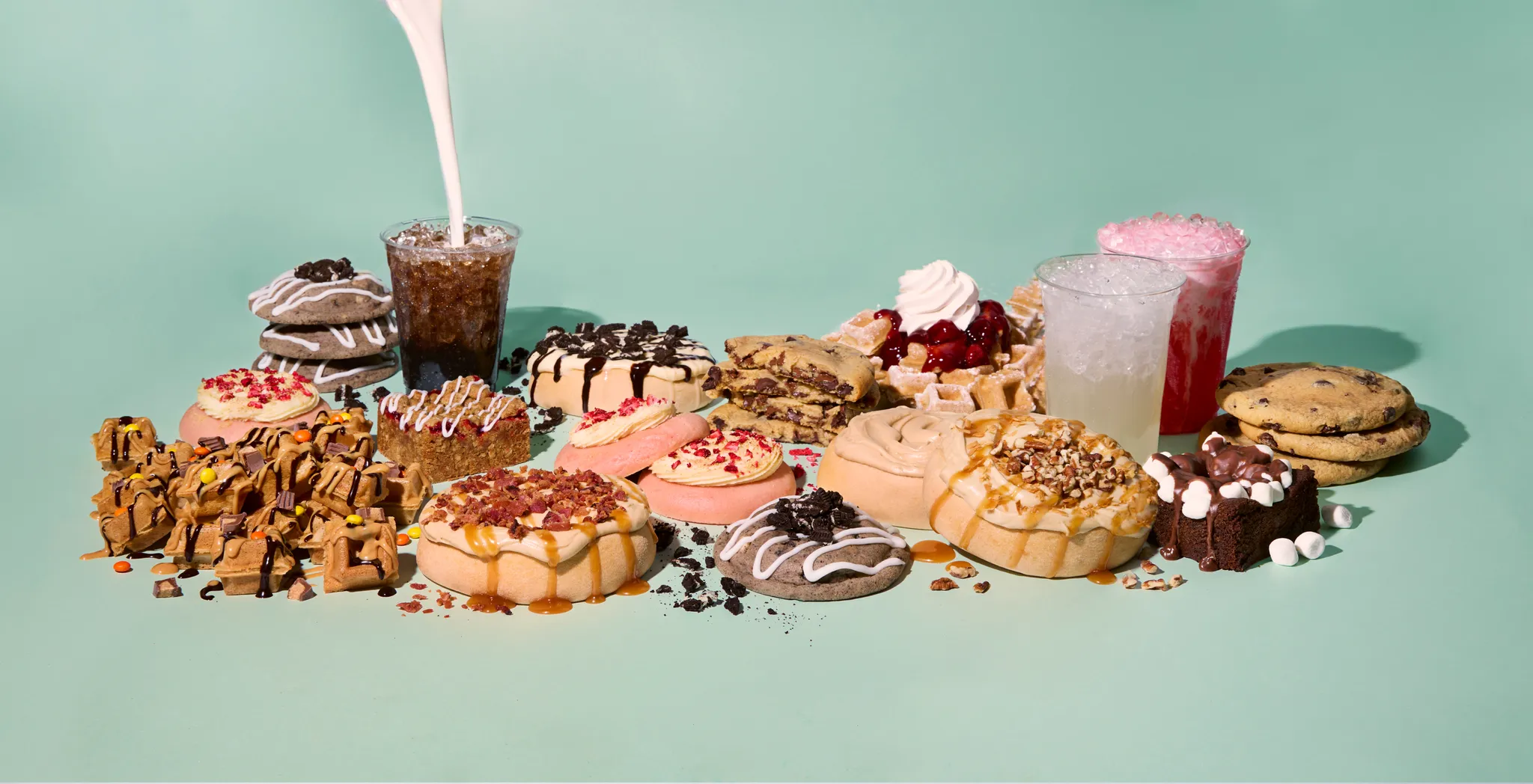 An over-the-top spread of Dirty Dough stuffed cookies, waffle bites, brownies and drinks with a pour of cold milk